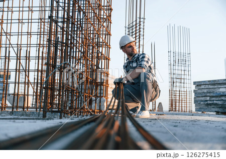 Working with metal material. Man is on the construction site at daytime Working with metal material. Man is on the construction site at daytime 126275415
