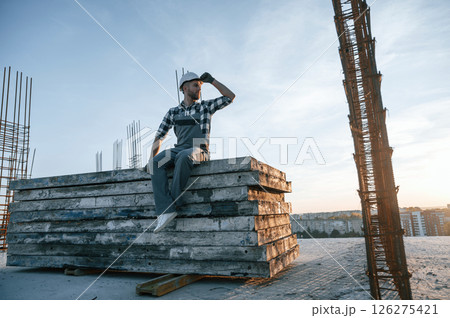 Sitting and looking to the side. Man is working on the construction site at daytime 126275421