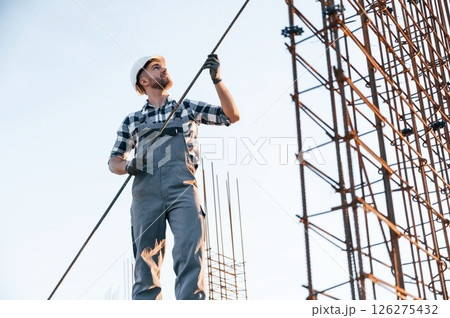 Holding metal object in hands. Man is working on the construction site at daytime 126275432