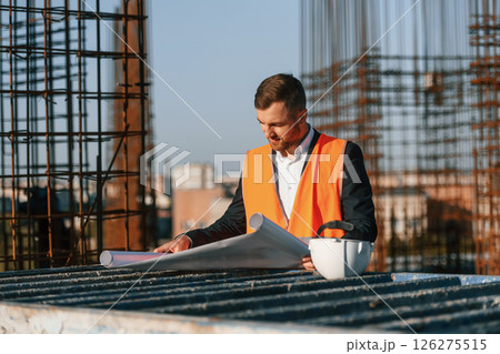 Man is working on the construction site at daytime. Reading the plan Man is working on the construction site at daytime. Reading the plan 126275515