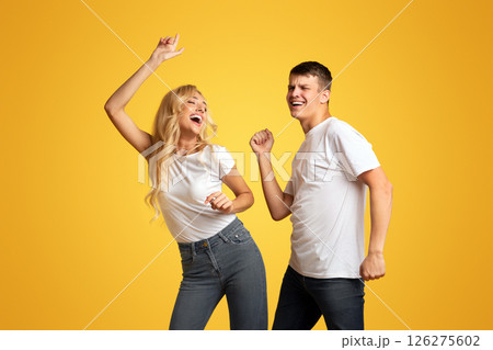 Dance Like Nobody's Watching. Emotional guy and girl having fun over yellow background, copy space Dance Like Nobody's Watching. Emotional guy and girl having fun over yellow background, copy space 126275602