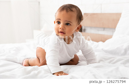 Cute African Little Baby Boy Crawling On Bed Looking Aside Posing In Bedroom At Home. Full Length Portrait Shot Of Adorable Toddler Kid. Sweet Childhood Moments, Child Care Concept 126275794