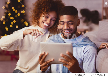 Loving man and woman choosing Christmas film on tablet, resting together at home Loving man and woman choosing Christmas film on tablet, resting together at home 126275821