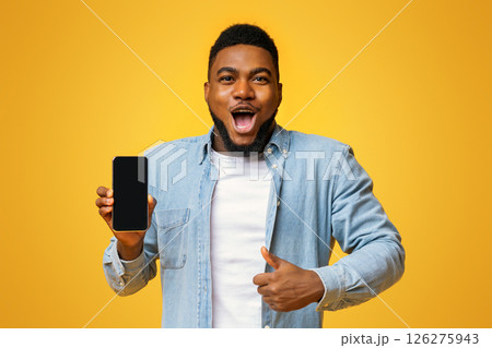 Wow, amazing app. Surprised african man holding smartphone with black screen and showing thumb up, yellow background with free space Wow, amazing app. Surprised african man holding smartphone with black screen and showing thumb up, yellow background with free space 126275943