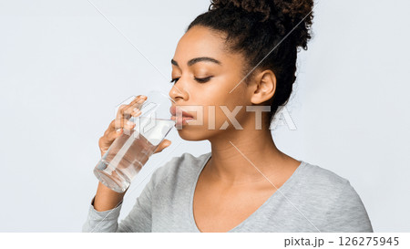 Thirsty young african woman holding glass of drinking water for body health, healthy lifestyle, thirst and hydration concept, free space 126275945