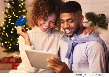 New year online shopping. Happy couple choosing gifts on tablet, enjoying evening at home New year online shopping. Happy couple choosing gifts on tablet, enjoying evening at home 126276000