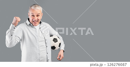 Mature Football Player. Excited cheering mature man posing with soccer ball on gray studio wall with winner gesture Mature Football Player. Excited cheering mature man posing with soccer ball on gray studio wall with winner gesture 126276087