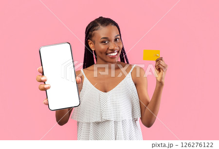 Electronic money concept. Happy young black woman holding credit card and showing thumb up gesture on pink studio background. Beautiful African American female recommending bank services 126276122