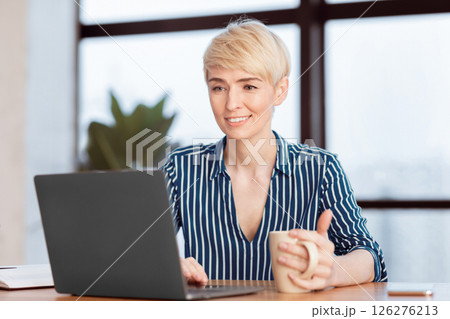 Happy Businesswoman At Laptop Working Browsing Internet Holding Coffee Cup Sitting In Modern Office. Selective Focus 126276213