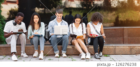 Preparing For Lectures. Group Of Multi-Ethnic Students Studying Together Outdoors, Using Laptop And Taking Notes To Workbooks, Panorama Preparing For Lectures. Group Of Multi-Ethnic Students Studying Together Outdoors, Using Laptop And Taking Notes To Workbooks, Panorama 126276238