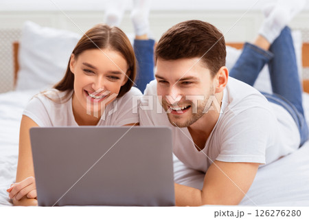 Weekend. Millennial Couple Using Laptop Lying In Bed Watching Movie Spending Weekend At Home. Selective Focus Weekend. Millennial Couple Using Laptop Lying In Bed Watching Movie Spending Weekend At Home. Selective Focus 126276280