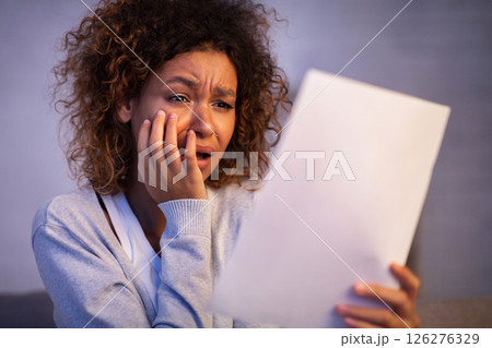 Disappointed woman reading letter of break up from boyfriend, girl covering mouth with hand 126276329