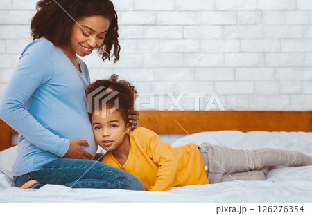 Motherhood And Pregnancy. Little African Daughter Listening To Mother's Pregnant Belly In Bed At Home 126276354