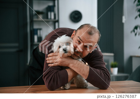 Man in casual clothes is indoors with his cute maltese dog 126276387