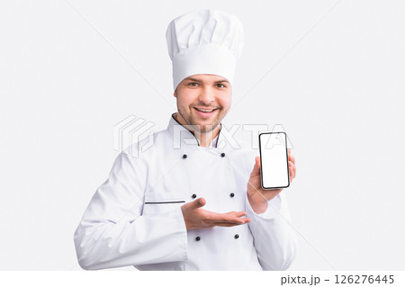 Restaurant Chef Showing Cellphone With Empty Screen Recommending Food Delivery Service Standing On White Studio Background. Panorama Restaurant Chef Showing Cellphone With Empty Screen Recommending Food Delivery Service Standing On White Studio Background. Panorama 126276445