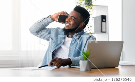 Time for family. Smiling african american employee talking on cellphone, calling to his wife during working day in office 126276540