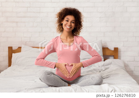 Maternity prenatal care. Expectant woman having heart shape with hands on her belly Maternity prenatal care. Expectant woman having heart shape with hands on her belly 126276810