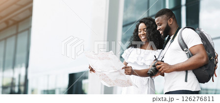 Black couple in casual clothes stands in front of a modern building, looking at a map, presumably planning their day exploring the city, copy space Black couple in casual clothes stands in front of a modern building, looking at a map, presumably planning their day exploring the city, copy space 126276811