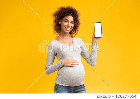 Cool app. Happy pregnant woman showing phone with blank screen over pink background Cool app. Happy pregnant woman showing phone with blank screen over pink background 126277054