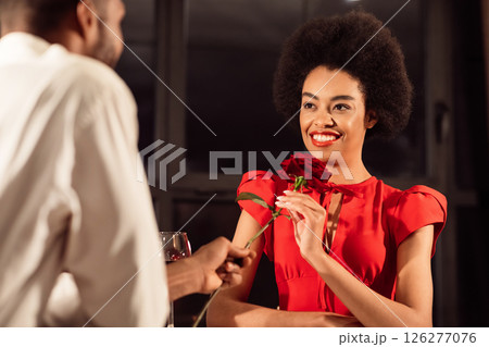 Romantic Date. Afro Man Giving Girlfriend Red Rose Flower Dining Celebrating Anniversary Or Valentine's Day Sitting In Restaurant In Evening Romantic Date. Afro Man Giving Girlfriend Red Rose Flower Dining Celebrating Anniversary Or Valentine's Day Sitting In Restaurant In Evening 126277076