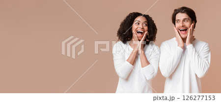 Unbelievable. Shocked interracial couple opening mouths and touching cheeks in amazement, standing together over yellow background, free space Unbelievable. Shocked interracial couple opening mouths and touching cheeks in amazement, standing together over yellow background, free space 126277153
