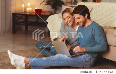 Happy Couple Using Laptop Computer Browsing Internet Sitting On Floor Indoor In Evening Happy Couple Using Laptop Computer Browsing Internet Sitting On Floor Indoor In Evening 126277158