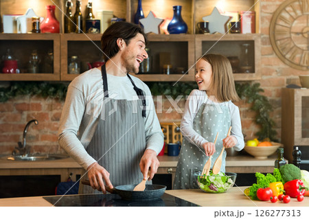 Happy father and little girl laughing while cooking lunch together, having fun in kitchen, mixing dough in bowl. Happy father and little girl laughing while cooking lunch together, having fun in kitchen, mixing dough in bowl. 126277313