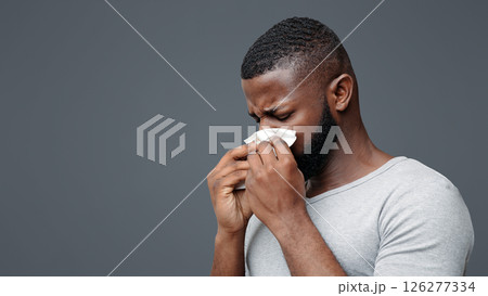 Afro man touching his nose with napkin, having runny nose, got flue, free space Afro man touching his nose with napkin, having runny nose, got flue, free space 126277334