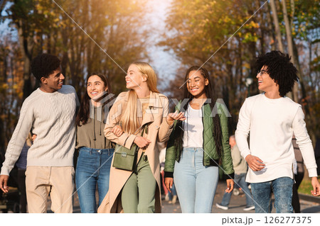 Positive international students walking by public park, spending weekend together 126277375