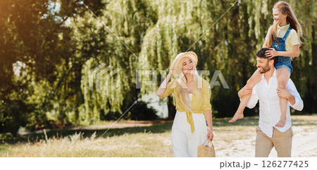 Family Summer. Relaxed Parents And Little Daughter Walking Outdoors In Countryside Going On Picnic After Quarantine Reopening. Family Summer. Relaxed Parents And Little Daughter Walking Outdoors In Countryside Going On Picnic After Quarantine Reopening. 126277425