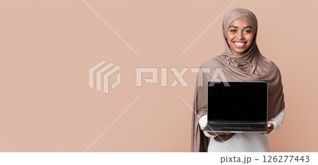 Cool Website. Smiling Black Muslim Girl In Hijab Holding Laptop Computer With Blank Black Screen For Mockup, Standing Over Yellow Background Cool Website. Smiling Black Muslim Girl In Hijab Holding Laptop Computer With Blank Black Screen For Mockup, Standing Over Yellow Background 126277443