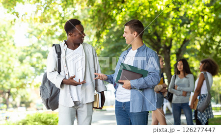 Two international students guys having conversation at public park, having break while studying Two international students guys having conversation at public park, having break while studying 126277447