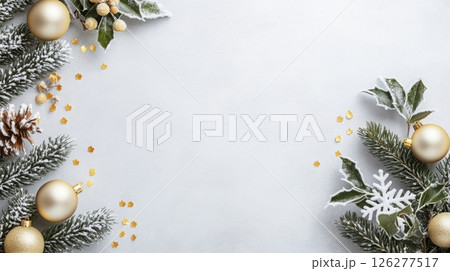 A collection of winter decorations creates a festive atmosphere. Gold ornaments are nestled among pine branches, greenery, and delicate snowflakes, set against a light-colored background. 126277517