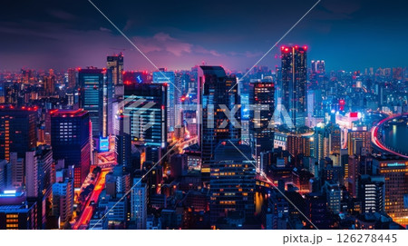 A night view of Tokyo's skyline, showing brightly lit skyscrapers and illuminated streets. A bridge stretches across a river in the distance. 126278445