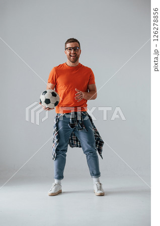 Standing and holding soccer ball. Handsome man is in the studio against white background Standing and holding soccer ball. Handsome man is in the studio against white background 126278856