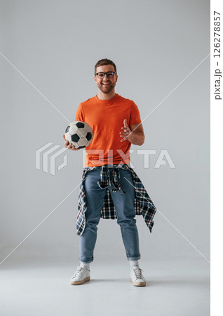 Standing and holding soccer ball. Handsome man is in the studio against white background 126278857