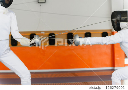 Close-up of fencing swords crossing during intense match indoors 126279001
