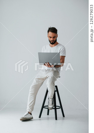 On the chair with laptop. Handsome man is in the studio against white background 126279033