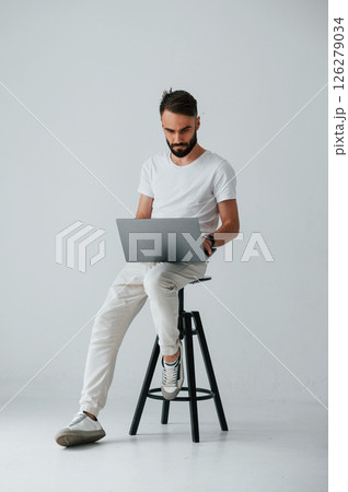 On the chair with laptop. Handsome man is in the studio against white background 126279034