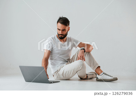 Silver colored laptop in hands. Handsome man is in the studio against white background Silver colored laptop in hands. Handsome man is in the studio against white background 126279036