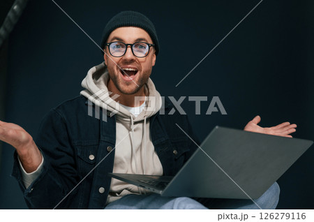 Celebrating success. Feeling uplifting. Using laptop. Handsome man is in the studio against background 126279116