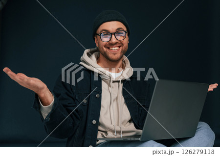 Smiling, sitting and using laptop. Handsome man is in the studio against background Smiling, sitting and using laptop. Handsome man is in the studio against background 126279118
