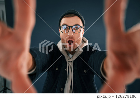 Making the photo by hands, pretending. Smiling. Handsome man is in the studio against blue background Making the photo by hands, pretending. Smiling. Handsome man is in the studio against blue background 126279186