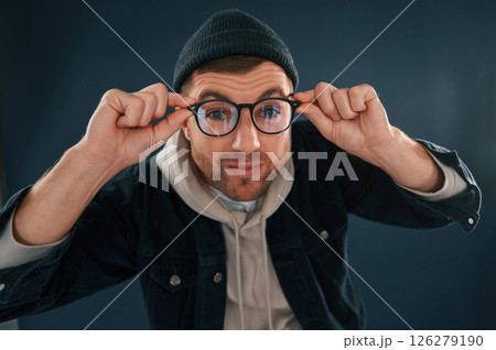Funny guy playing with glasses. Handsome man is in the studio against blue background 126279190