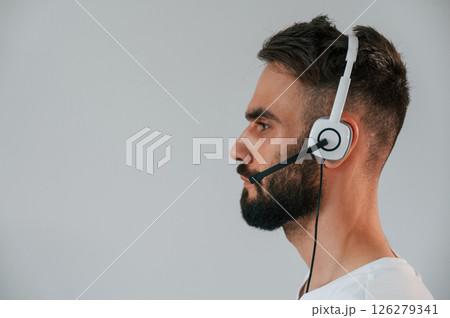 Side view. In headset. Handsome man is in the studio against white background 126279341