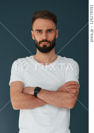 With arms crossed. Handsome man is in the studio against blue background 126279391