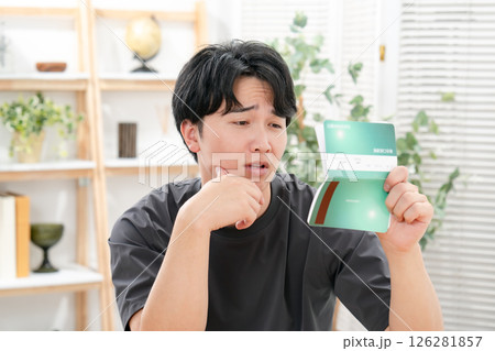 通帳を持って悩む男性 126281857