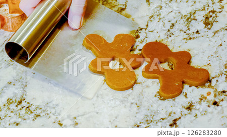 Using various festive cookie cutters, we're cutting out charming gingerbread cookies from the rolled dough on the sleek marble counter, bringing holiday cheer to the modern kitchen. Using various festive cookie cutters, we're cutting out charming gingerbread cookies from the rolled dough on the sleek marble counter, bringing holiday cheer to the modern kitchen. 126283280