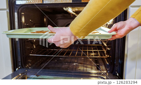 Scrumptious gingerbread cookies getting baked to perfection in a gas oven, filling the kitchen with warm, aromatic holiday bliss. 126283294