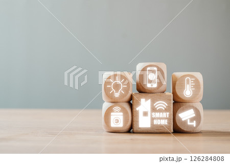 Wooden blocks with smart home icons symbolize automation, security, and energy efficiency in a modern household setting. 126284808